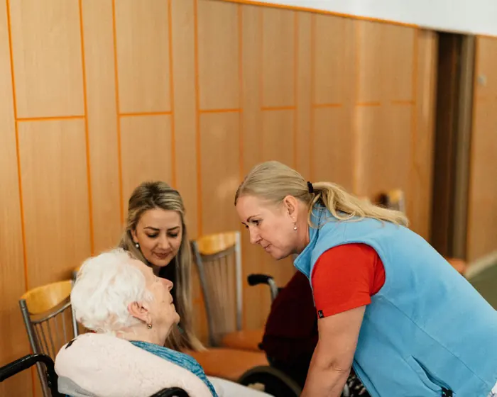 Carers talking with residents in wheelchairs in a care home