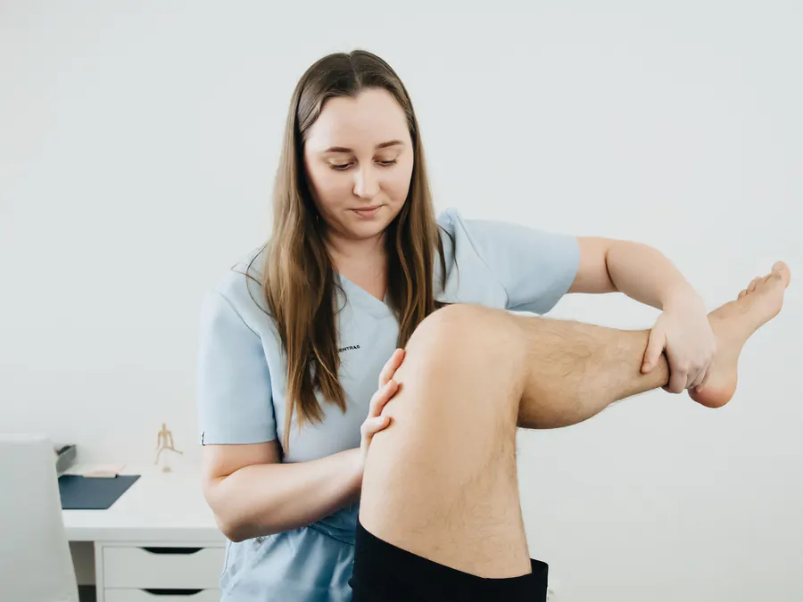 Physiotherapist bending a patient's knee and hip in a gentle range-of-motion exercise after surgery